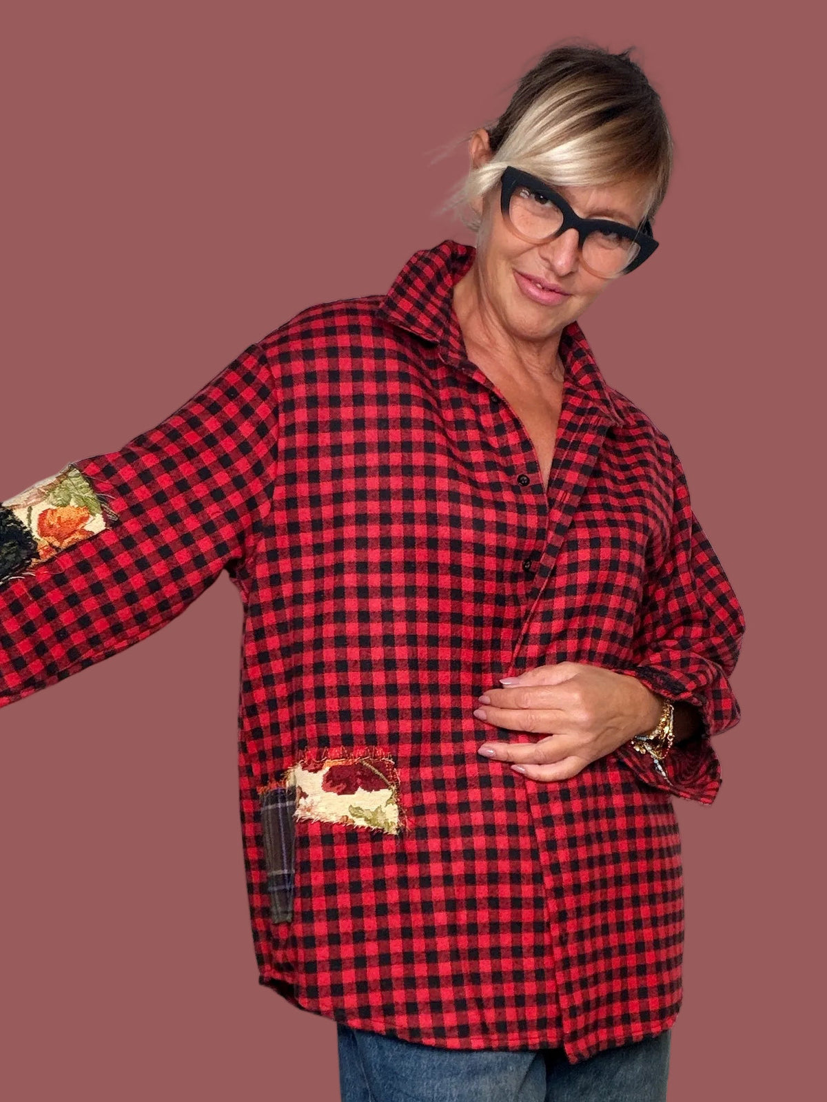 Camicia a quadri rossi e neri over con inserti patch decorativi, indossata, vista frontale con braccia aperte