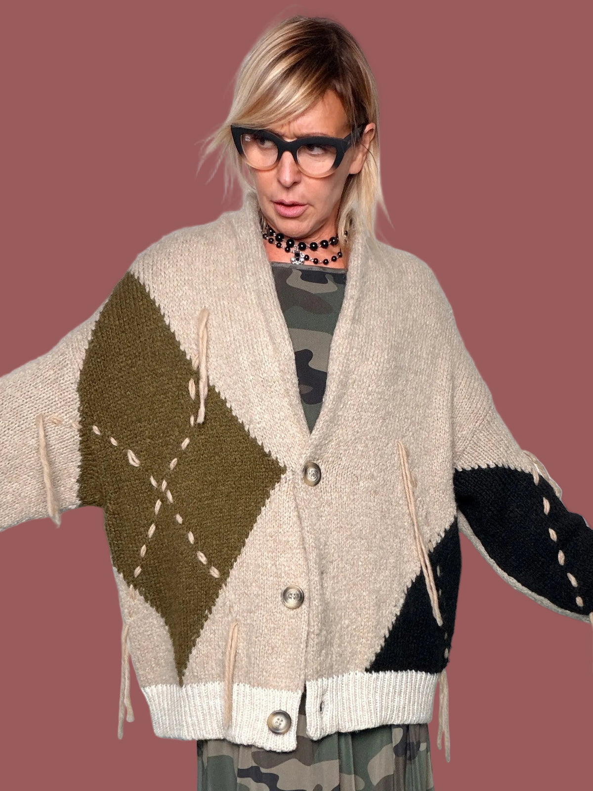 Cardigan beige con rombo militare sul davanti, portato aperto sopra abito militare con cintura, vista frontale