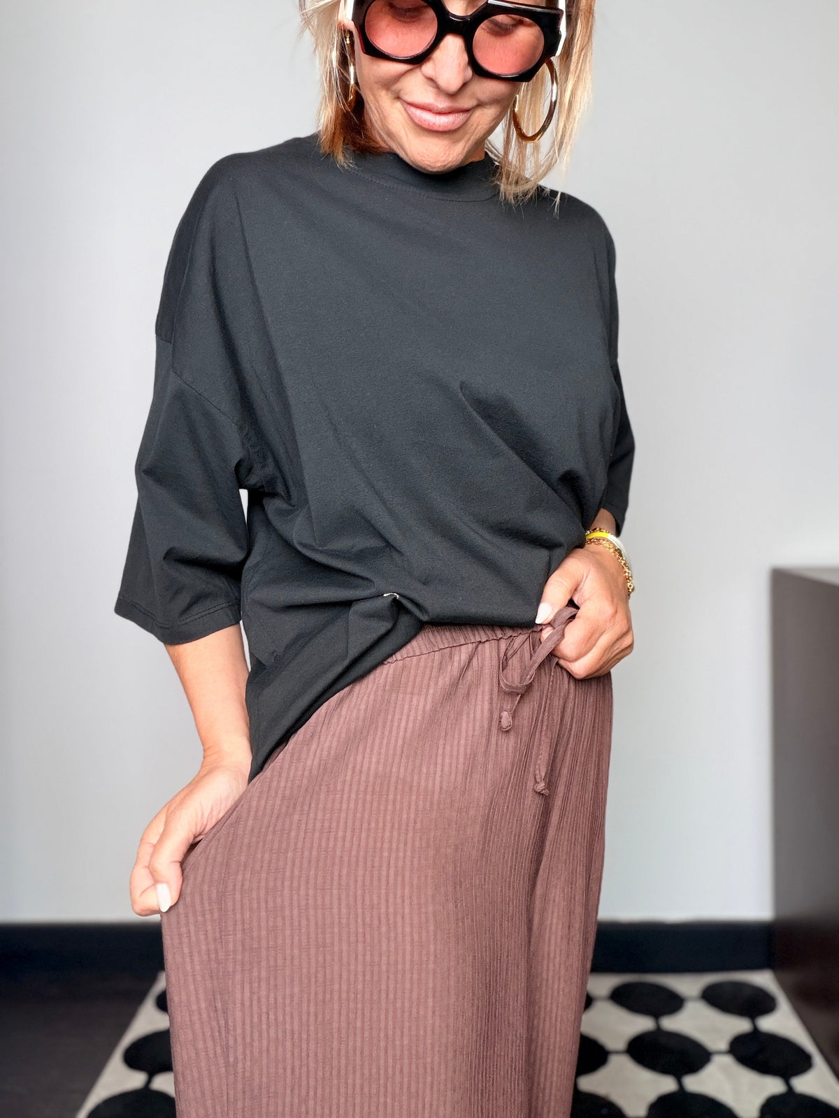 Pantalone plissé marrone cioccolato con t-shirt nera - vista frontale sorridente