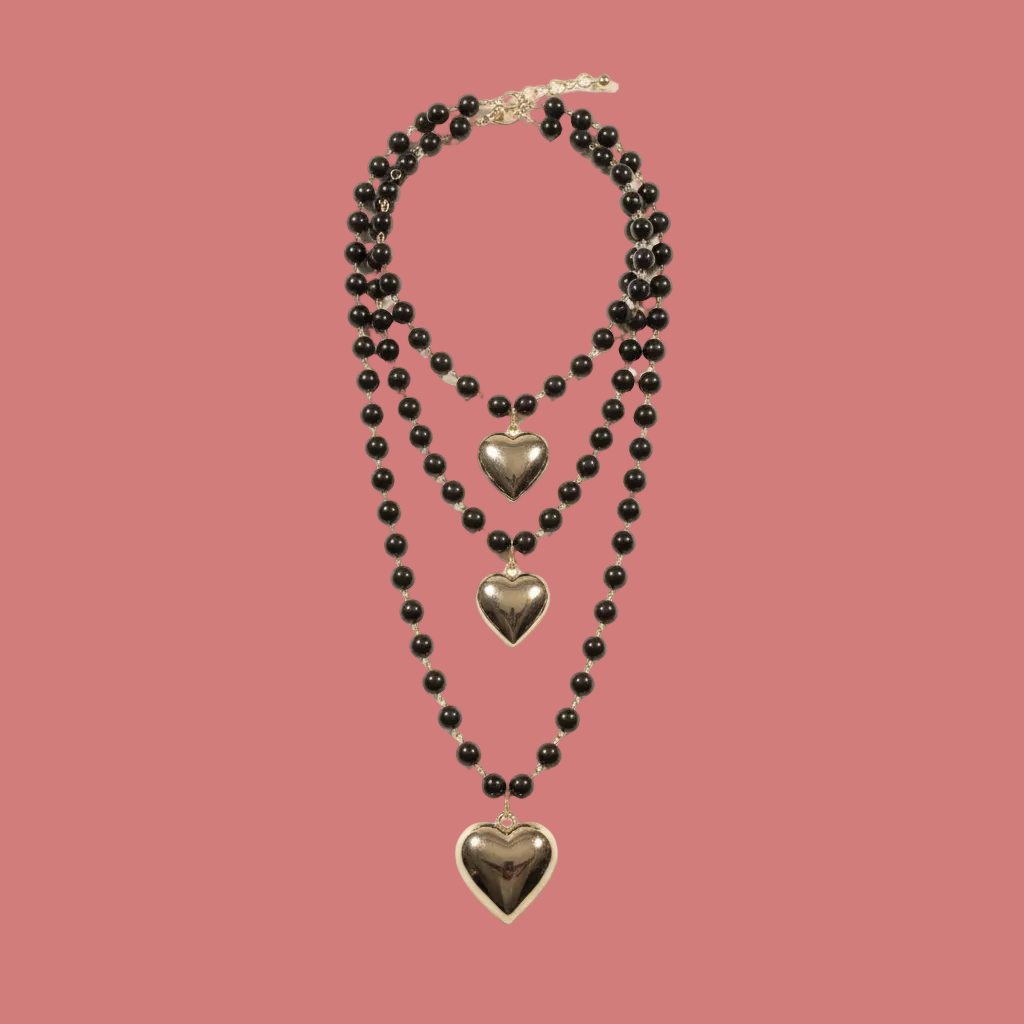Collana multistrato nera con tre pendenti a cuore su fondo neutro