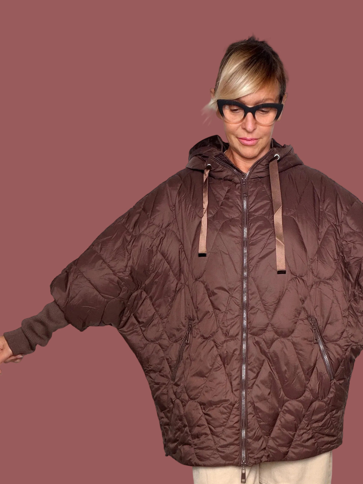 Piumino oversize imbottito a rombi marrone con cappuccio e chiusura zip, indossato davanti