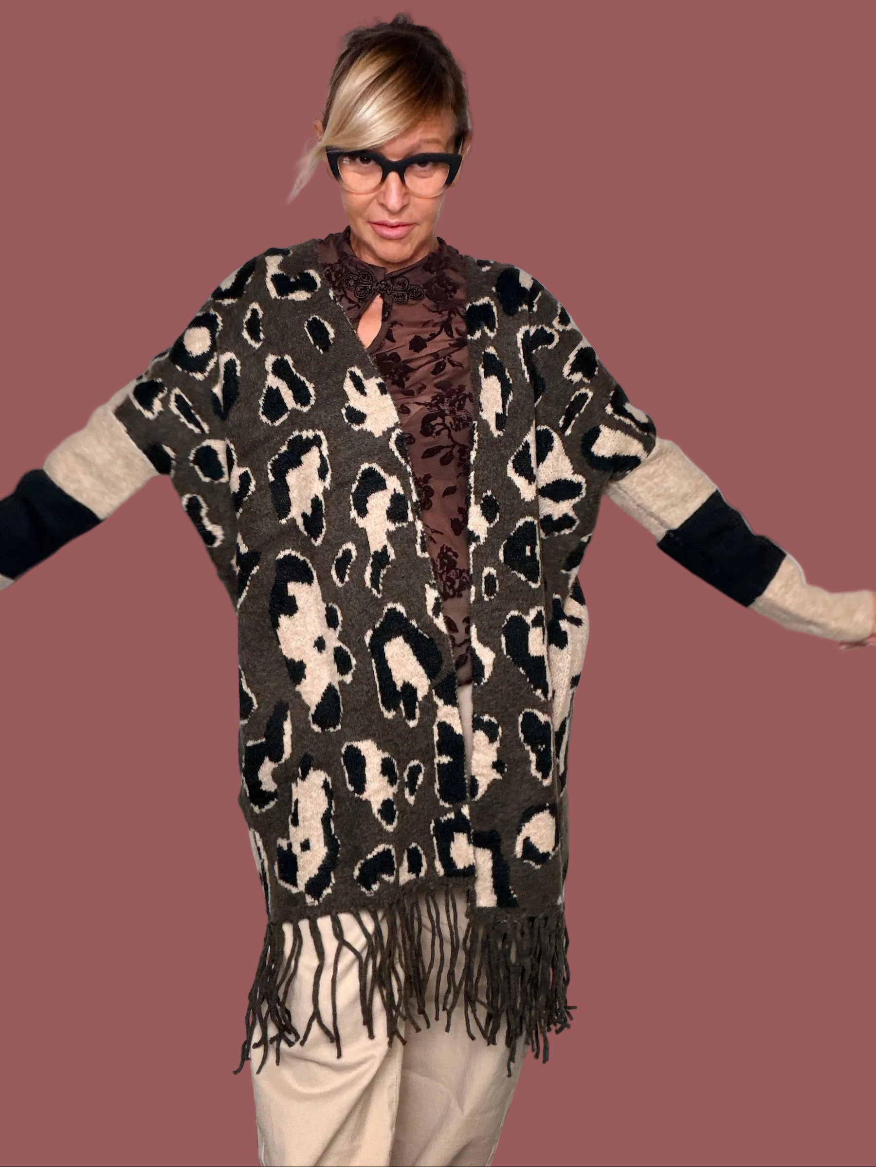 Cardigan lungo in maglia animalier moro con maniche crema e nere e frangia, indossato, vista frontale con braccia aperte
