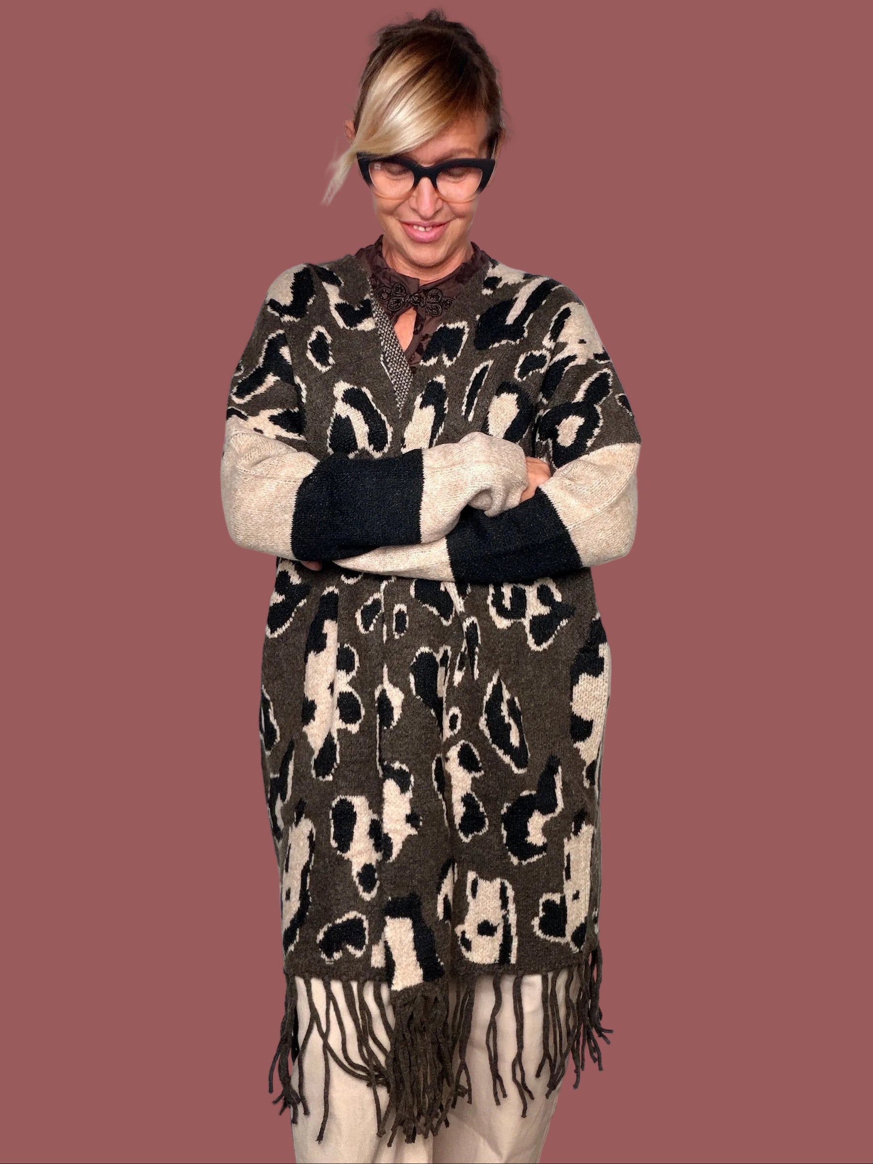 Cardigan lungo in maglia animalier moro con maniche crema e nere e frangia, indossato, vista frontale con braccia incrociate