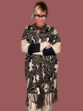 Cardigan lungo in maglia animalier moro con maniche crema e nere e frangia, indossato, vista frontale con braccia incrociate