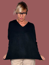 Maglia nera over con scollo a V e fondo a costina, indossata con pantalone beige, vista frontale