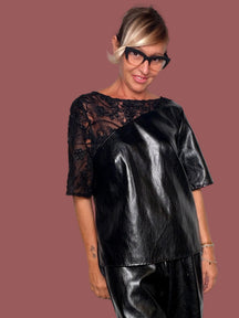 Maglia cubetto ecopelle nero con spalla e manica in pizzo fiorato, indossata con bermuda coordinato, vista frontale