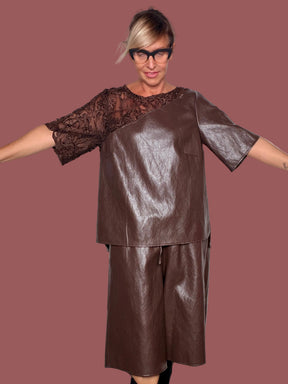 Bermuda ecopelle moro a gamba ampia con coulisse in vita, indossato con maglia coordinata, vista frontale con braccia aperte