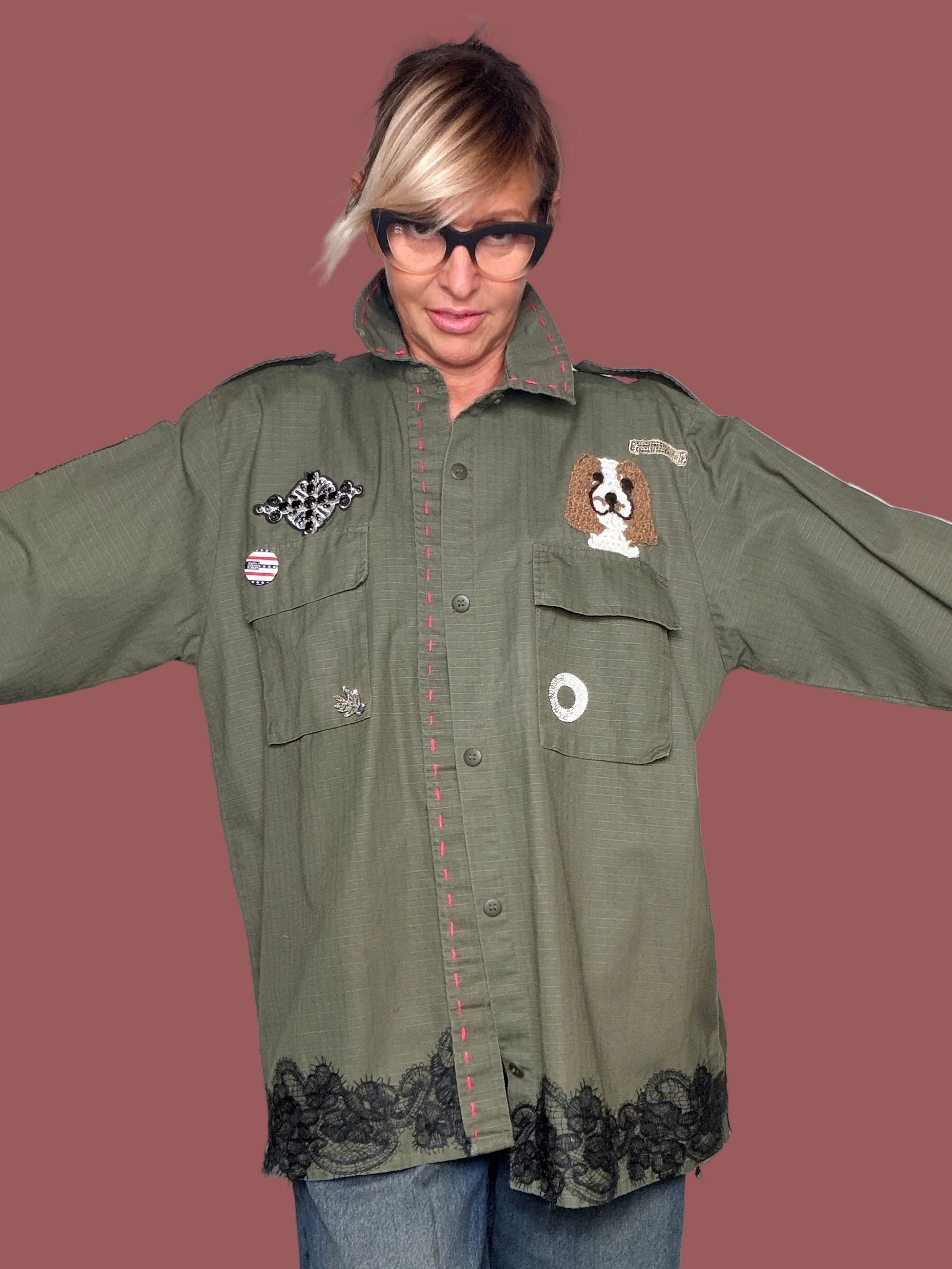 Giacca militare verde oliva con applicazione cerbiatto in strass e pizzo nero sul fondo, vista posteriore