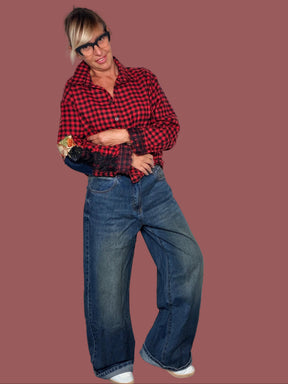 Jeans blu slavato a gamba ampia con cinque tasche, indossato con camicia vichy rossa, vista frontale leggermente di lato