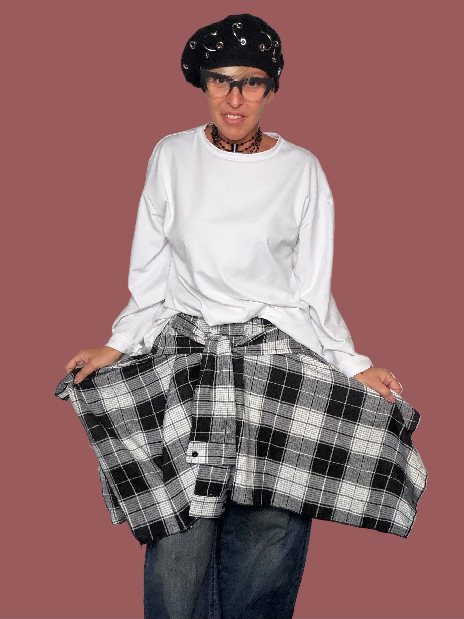 Gonna in quadri scozzesi nero e bianco con falda ampia annodata in vita, portata sopra jeans, vista frontale