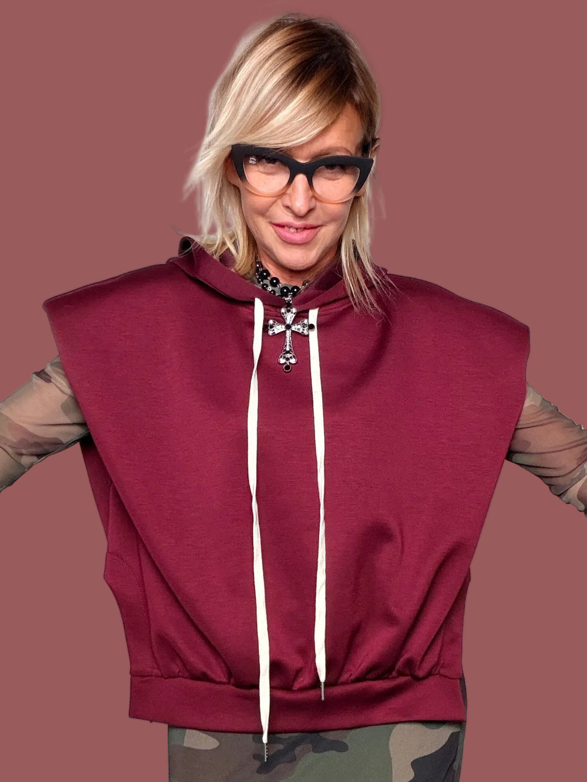 Felpa con cappuccio melanzana senza maniche con coulisse bianche, portata sopra top in tulle camouflage e gonna coordinata, vista frontale