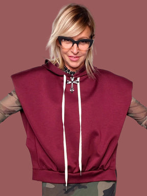 Felpa con cappuccio melanzana senza maniche con coulisse bianche, portata sopra top in tulle camouflage e gonna coordinata, vista frontale
