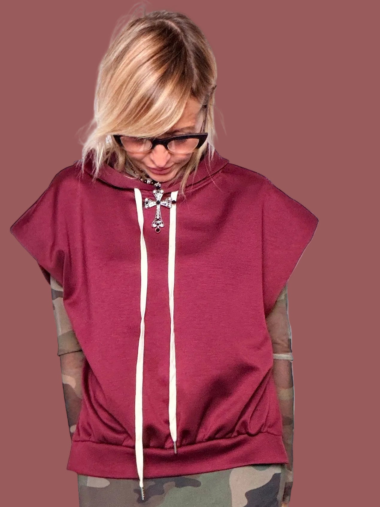 Felpa con cappuccio melanzana senza maniche con coulisse bianche, portata sopra top in tulle camouflage e gonna coordinata, vista frontale con braccia aperte