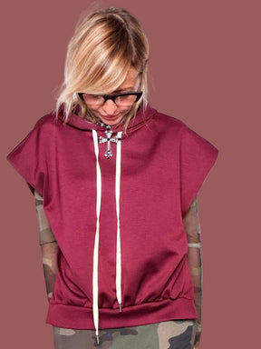 Felpa con cappuccio melanzana senza maniche con coulisse bianche, portata sopra top in tulle camouflage e gonna coordinata, vista frontale con braccia aperte