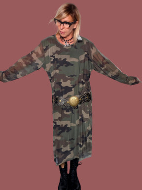 Abito camouflage semitrasparente con maniche lunghe, portato con gonna camouflage coordinata, vista di tre quarti con mano sul fianco