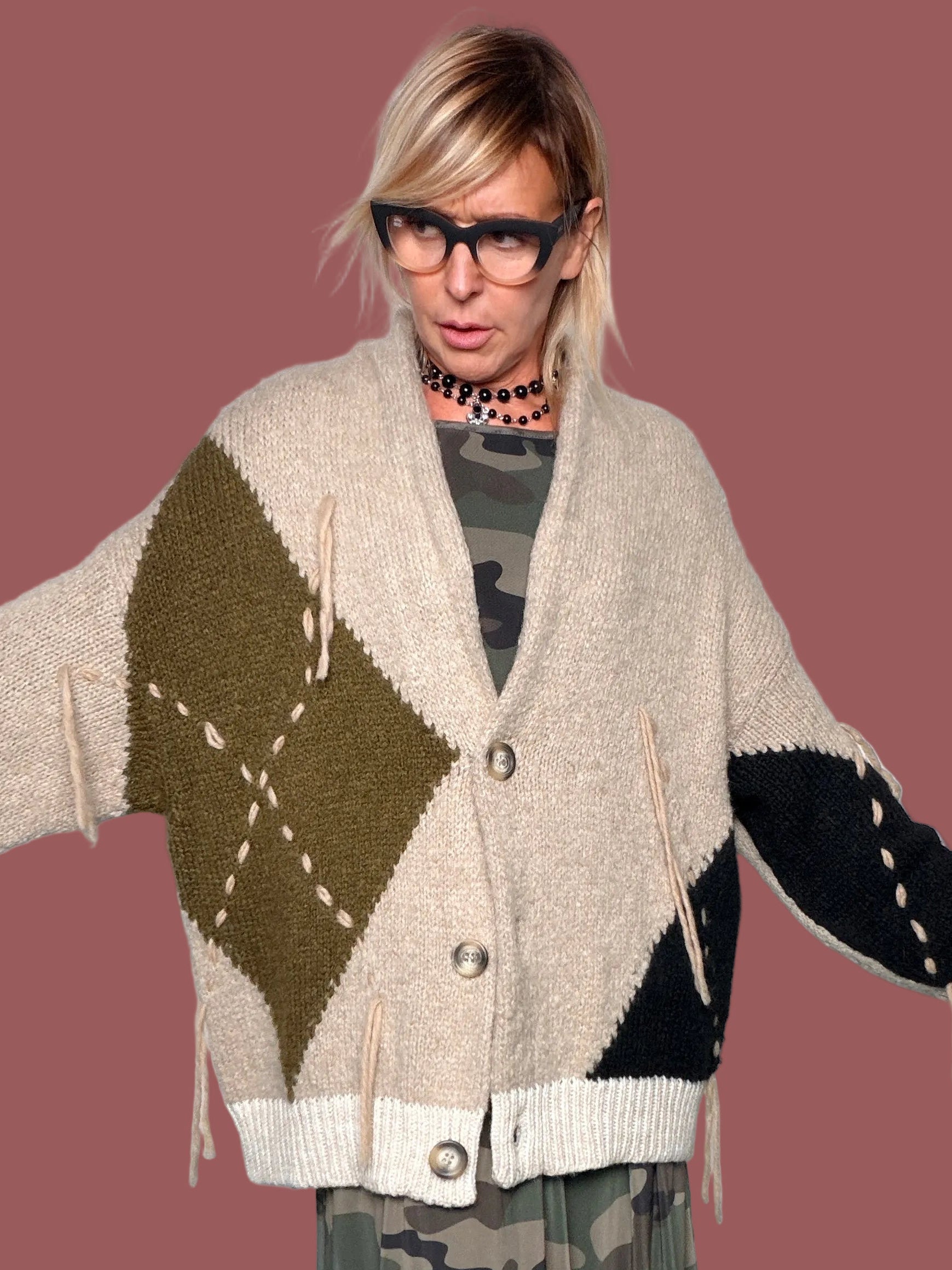 Cardigan beige con rombo militare sul davanti, portato aperto sopra abito militare con cintura, vista frontale