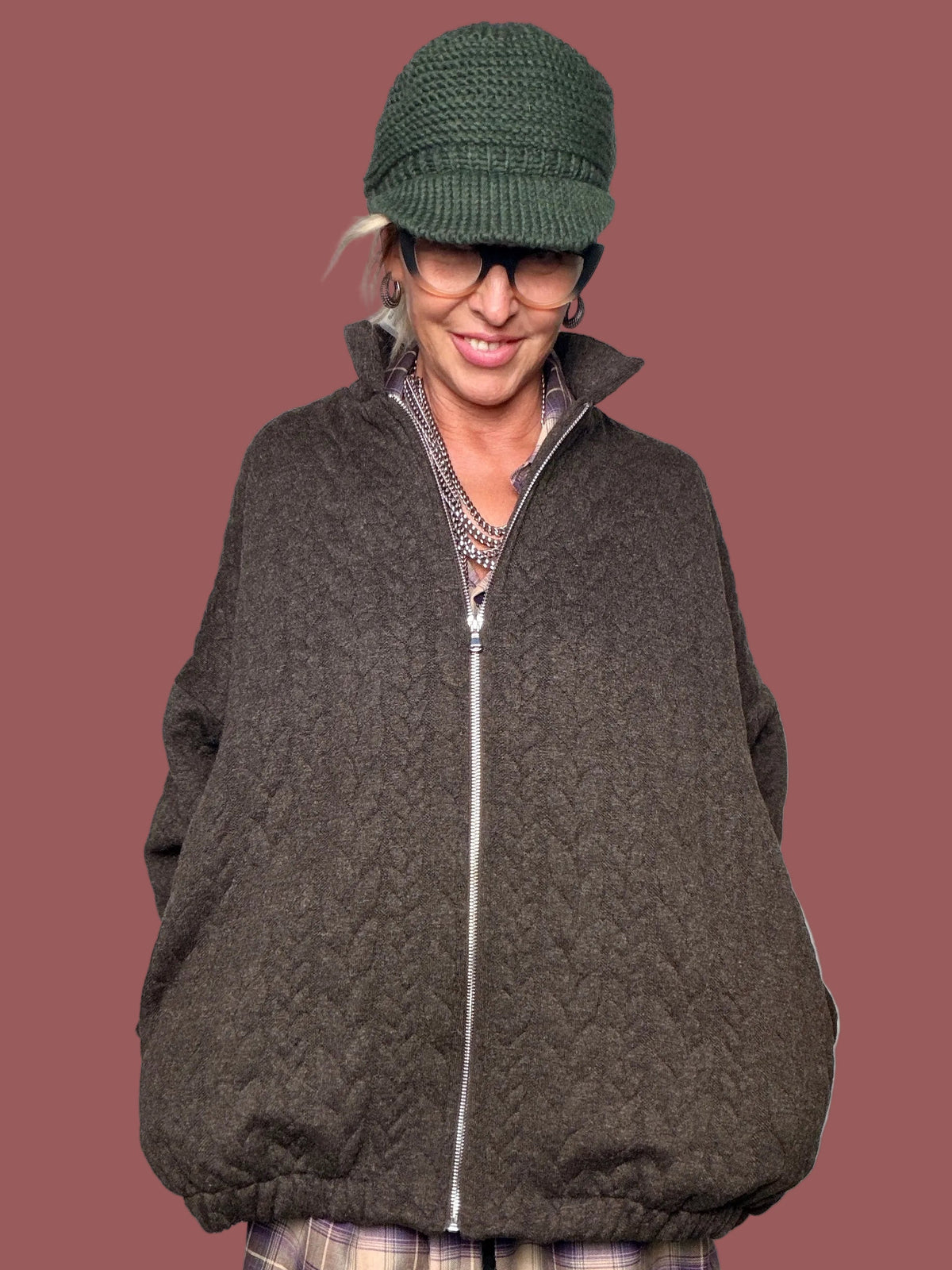 Giacca marrone trapuntata con collo alto e chiusura con zip, indossata con gonna a quadri