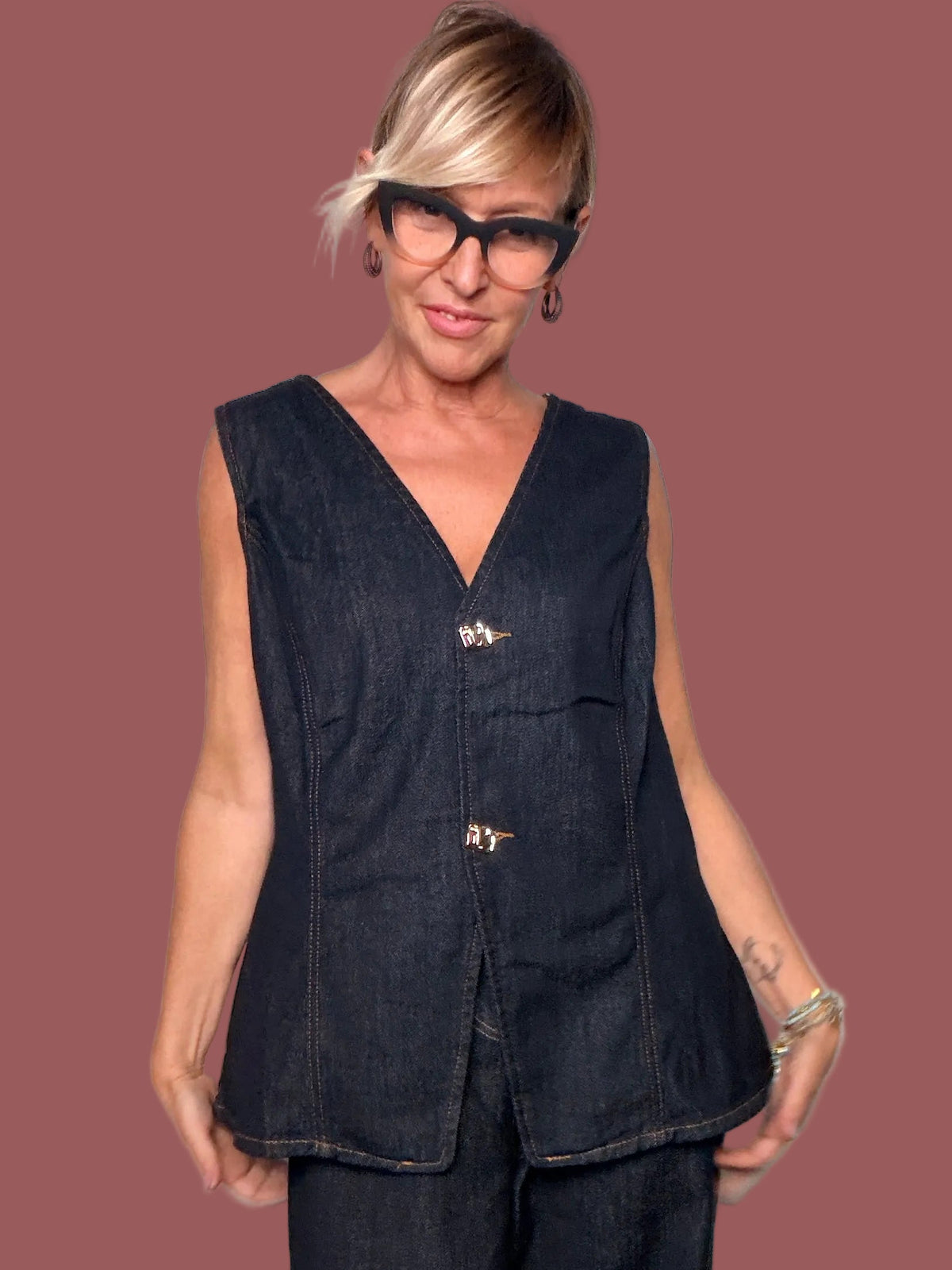 Dettaglio del gilet in denim blu scuro con chiusure decorative e cuciture a contrasto