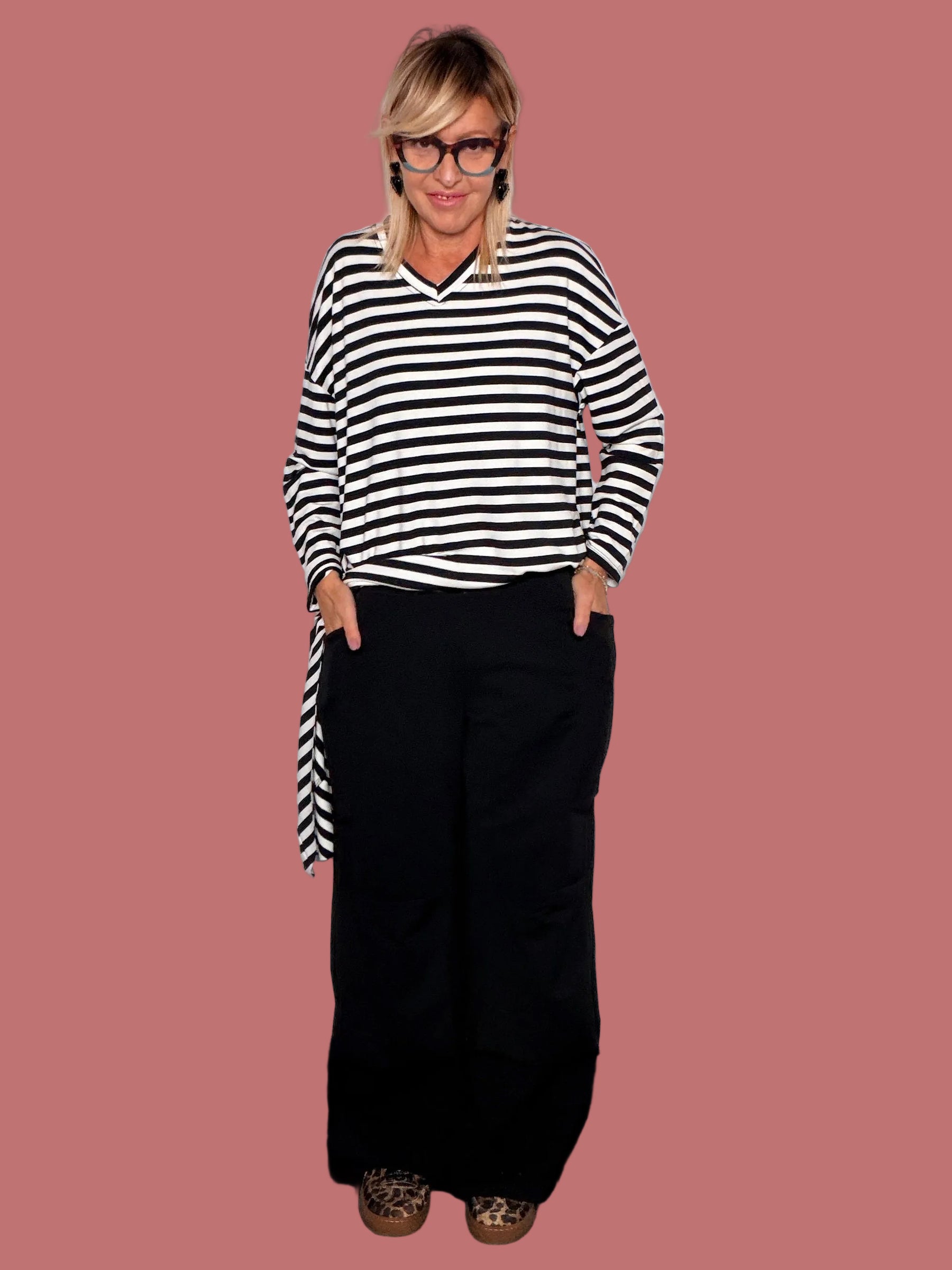 Pantaloni palazzo neri indossati con top a righe, dettaglio tasca