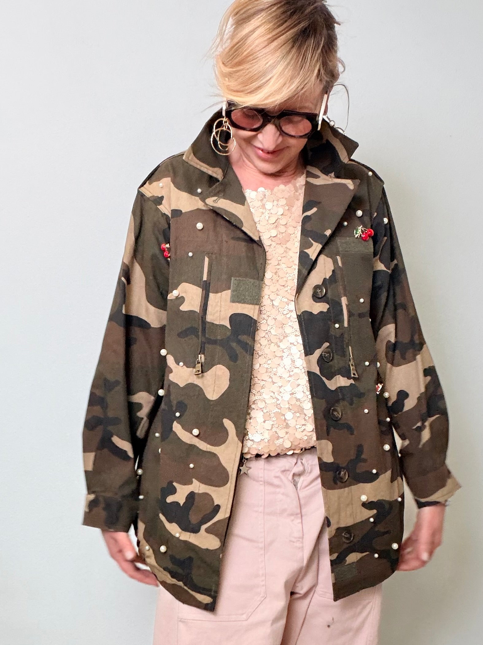Giacca oversize camouflage verde militare con perle applicate e spille ciliegie rosse.