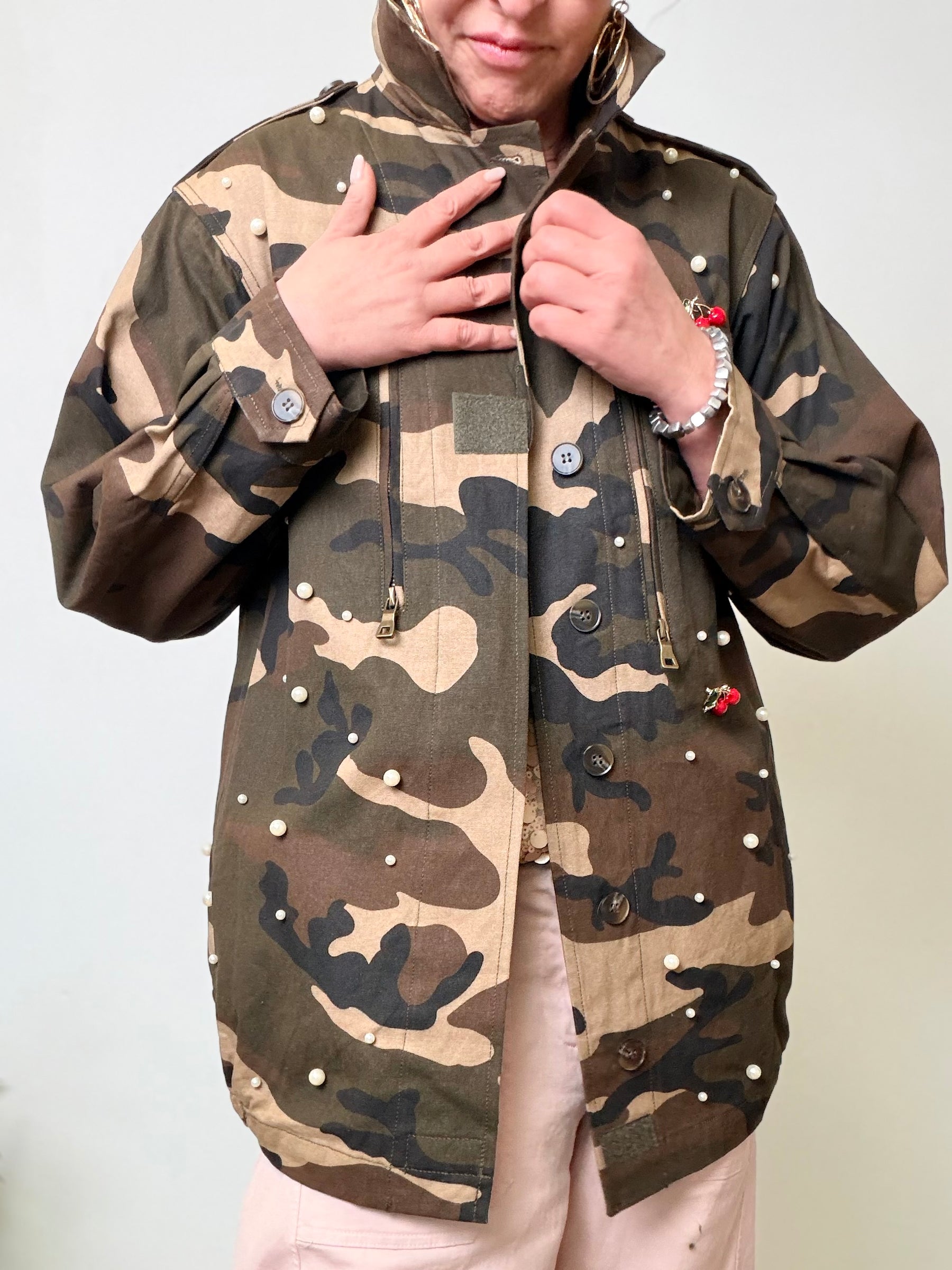 Giacca oversize camouflage verde militare con perle applicate e spille ciliegie rosse.