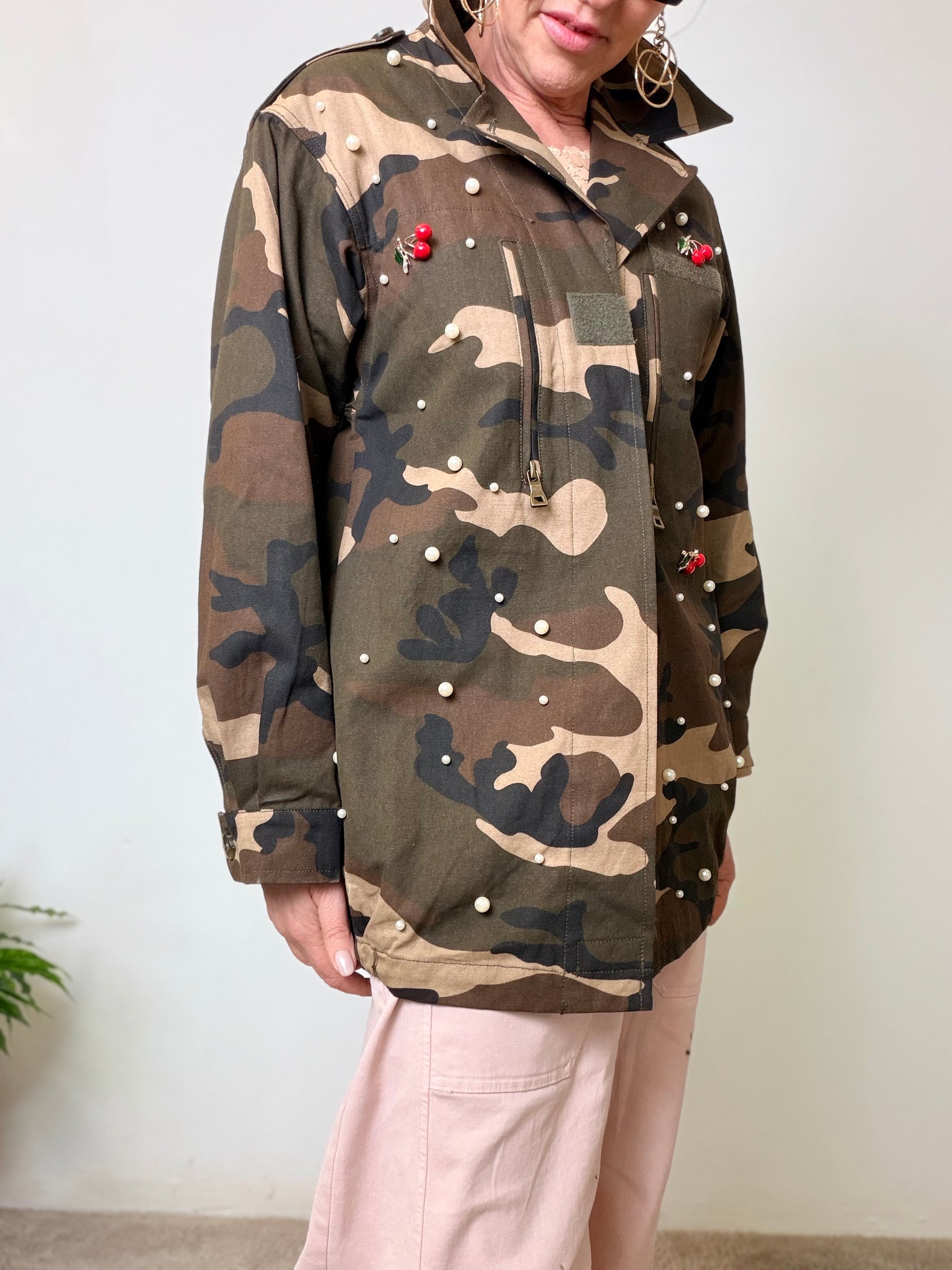 Giacca oversize camouflage verde militare con perle applicate e spille ciliegie rosse.