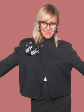 Giacca nera cropped con fiore applicato sulla spalla, vista frontale