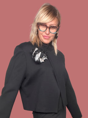 Giacca nera cropped con fiore applicato sulla spalla, vista laterale