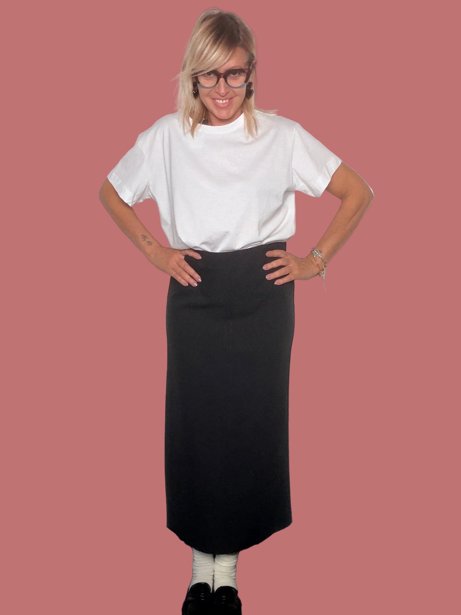 Gonna matita nera con t-shirt bianca, vista frontale con mani sui fianchi