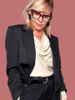 Giacca blazer corta nera indossata aperta sopra una blusa chiara