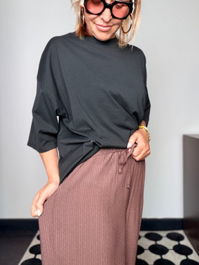Pantalone plissé marrone cioccolato con t-shirt nera - vista frontale sorridente