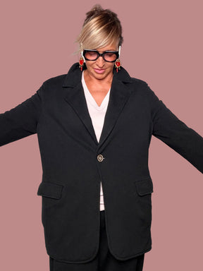 Giacca blazer felpa nera oversize - vista frontale braccia aperte con maglia rosa cipria e orecchini rossi