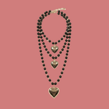 Collana multistrato nera con tre pendenti a cuore su fondo neutro